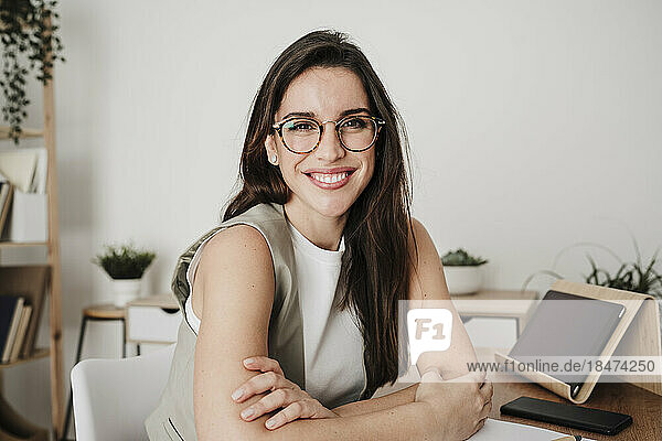 Happy businesswoman wearing eyeglasses at desk in office