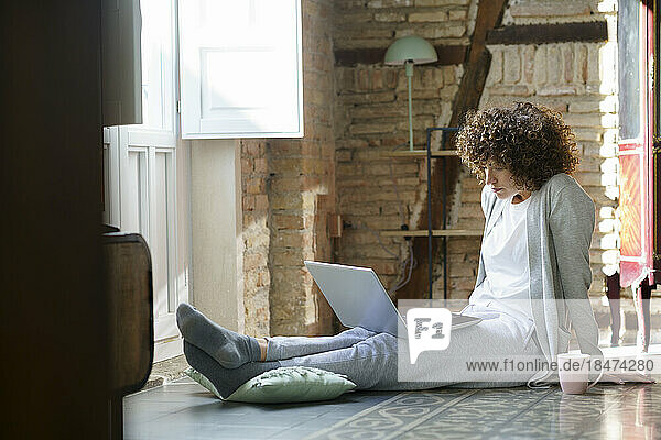 Freiberufler sitzt auf dem Boden und arbeitet zu Hause am Laptop
