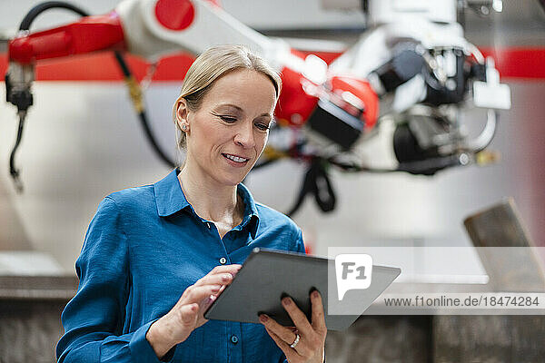 Technician using tablet PC in robot factory
