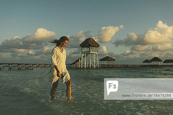 Young woman walking in sea near beach at dawn