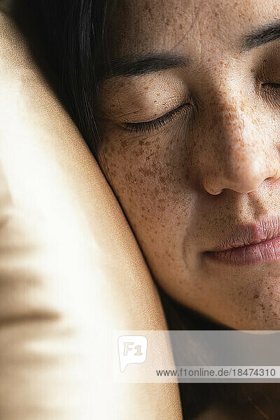 Woman with eyes closed resting on pillow