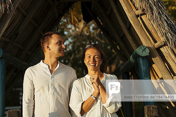 Happy couple enjoying together near thatched roof