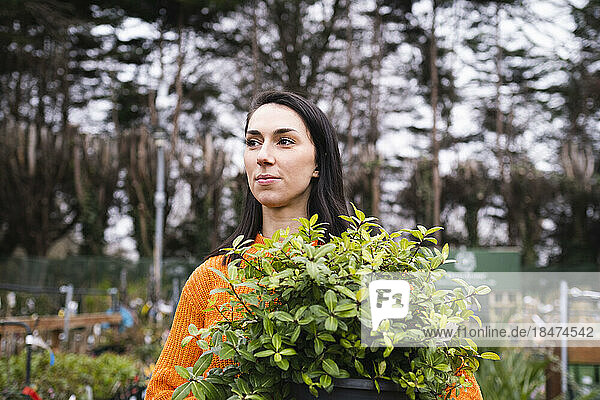 Young woman with potted plant in garden center