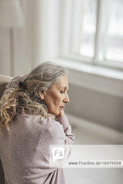 Contemplative woman with gray hair at home