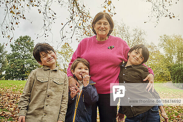 Lächelnde ältere Frau steht mit Enkeln im Park