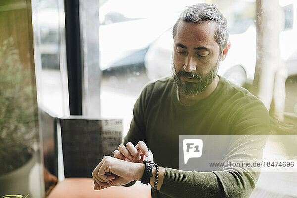 Man with beard checking time on wrist watch