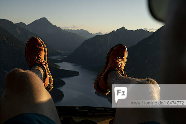 Sportschuhe eines Mannes  der bei Sonnenuntergang auf einem Berg sitzt
