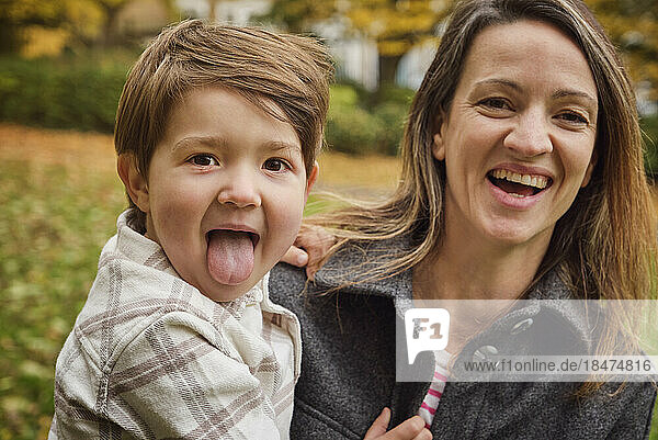 Son sticking out tongue by happy mother at park