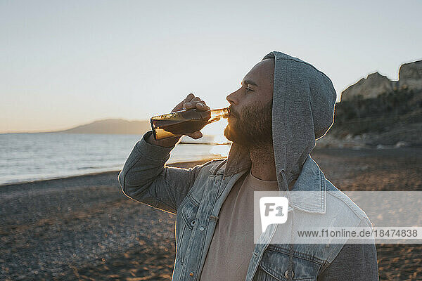 Mann trinkt Bier am Strand