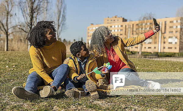 Glückliche Seniorin macht Selfie mit Tochter und Enkel im Park