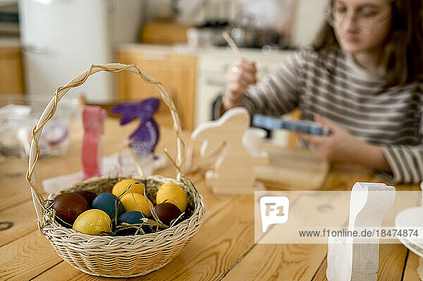 Colorful easter eggs in wicker basket on table at home