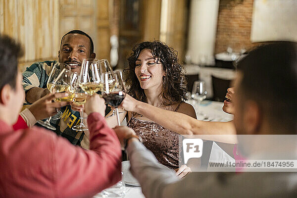 Happy multiracial friends toasting wineglasses at restaurant