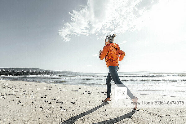 Mature woman jogging on shore at beach