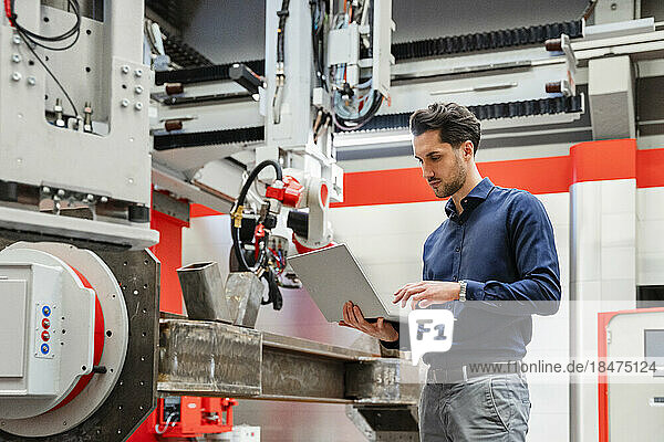 Engineer working on laptop in robot factory