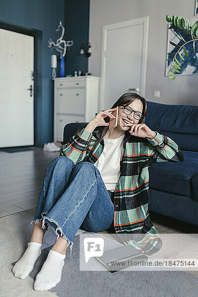 Happy woman wearing eyeglasses talking on smart phone sitting at home
