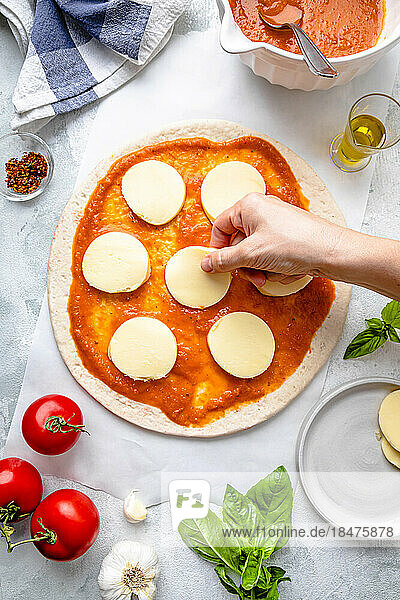 Hand of woman preparing pizza on table