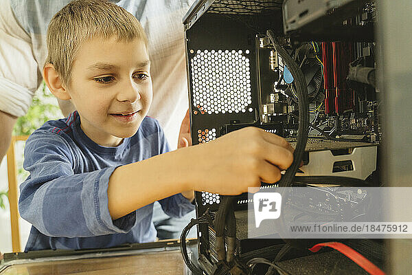 Smiling boy cleaning computer parts at home