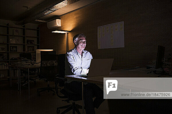 Happy senior businessman working late at workplace