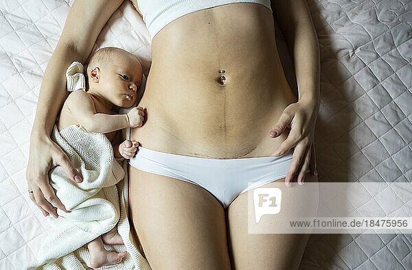 Baby boy lying next to mother with caesarean scar on belly