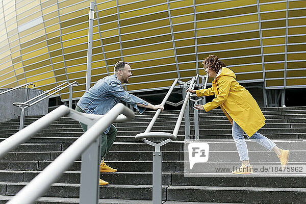 Happy couple playing on staircase outside stadium