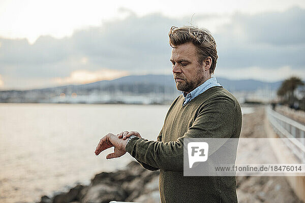 Mature man checking time in front of sea