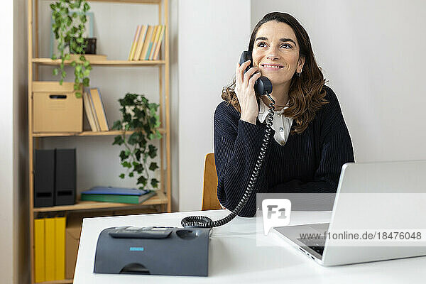 Happy businesswoman talking on phone in office