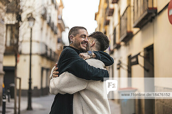 Happy gay couple hugging each other outside building