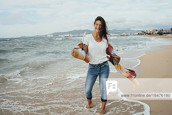 Smiling woman standing near seashore at beach