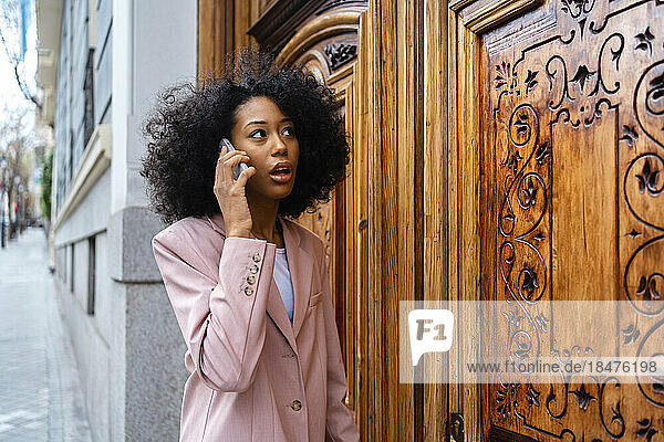 Businesswoman talking on smart phone standing by door