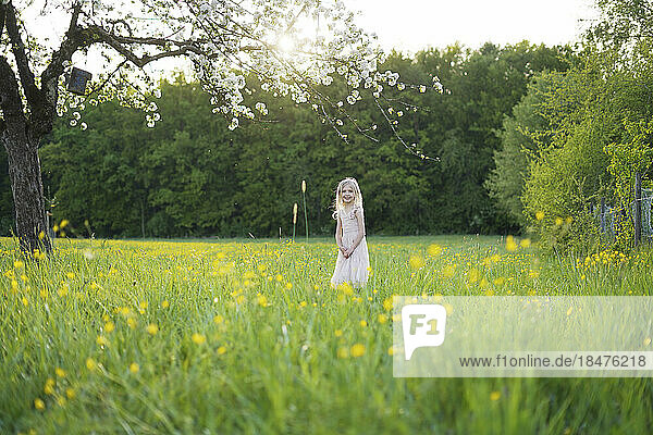 Girl standing amidst flowering plants at field
