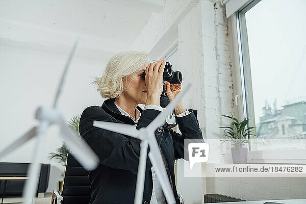 Businesswoman looking through binoculars at office