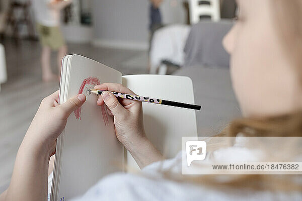 Girl drawing in book at home