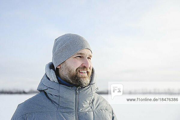 Happy man wearing knit hat in winter under sky