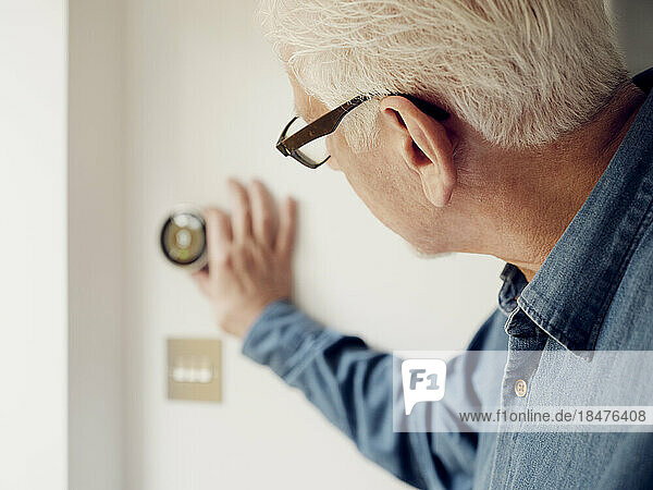 Älterer Mann passt die intelligente Thermostatsteuerung an der Wand zu Hause an