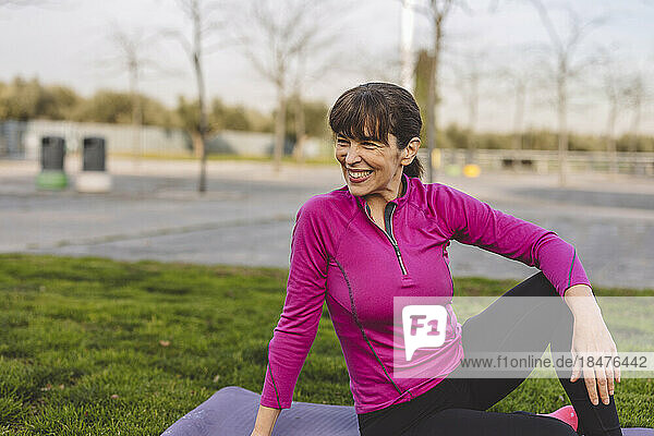 Happy mature woman sitting on exercise mat