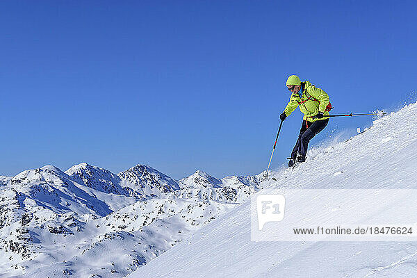 Österreich  Tirol  Skifahrerin rutscht den schneebedeckten Hang in den Kitzbüheler Alpen hinunter