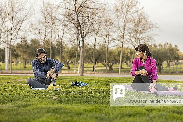 Happy mature couple practicing yoga in park