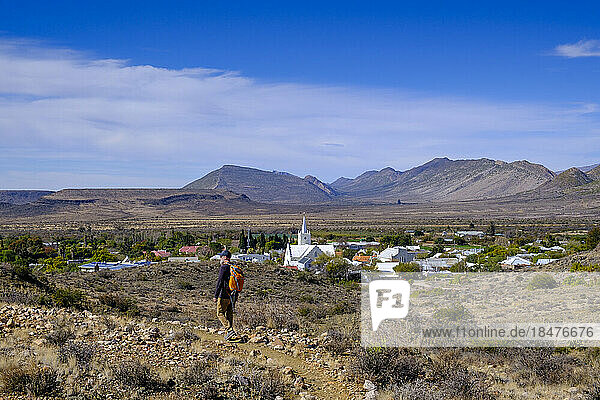 Südafrika  Provinz Westkap  Prince Albert  Wanderer auf dem Fußweg vor einer Wüstenstadt in der Großen Karoo