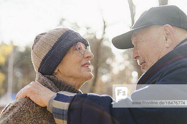 Senior couple wearing warm clothing talking to each other at park