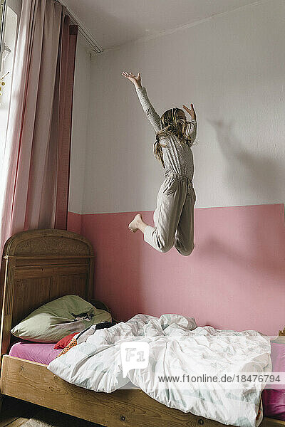 Sorgloses Mädchen springt zu Hause aufs Bett