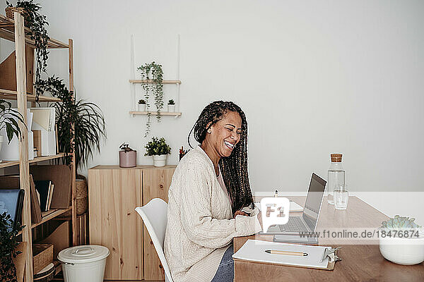 Happy freelancer with laptop sitting at desk