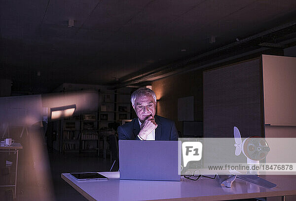 Businessman with hand on chin working late at office