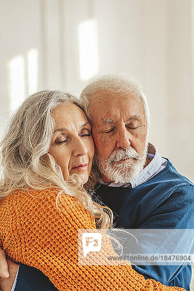 Liebevolles Seniorenpaar umarmt sich vor der Wand