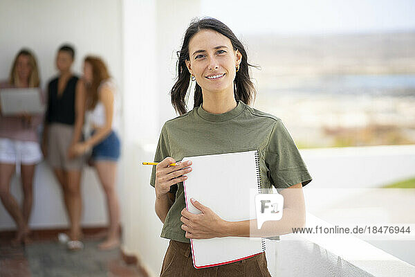 Smiling businesswoman holding spiral notebook