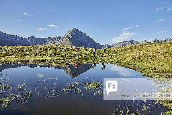 Austria  Tyrol  Group of hikers passing small alpine lake