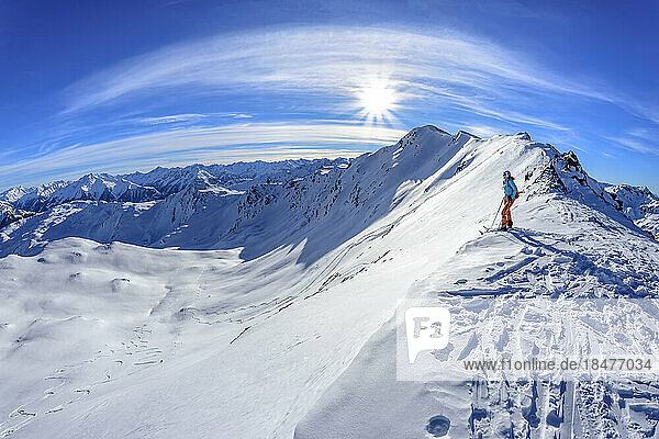 Austria  Tyrol  Sun shining over female skier admiring snowcapped landscape in Tux Alps