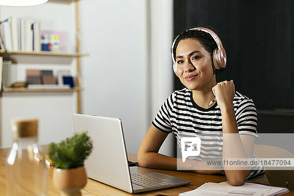 Thoughtful freelancer wearing wireless headphones at table