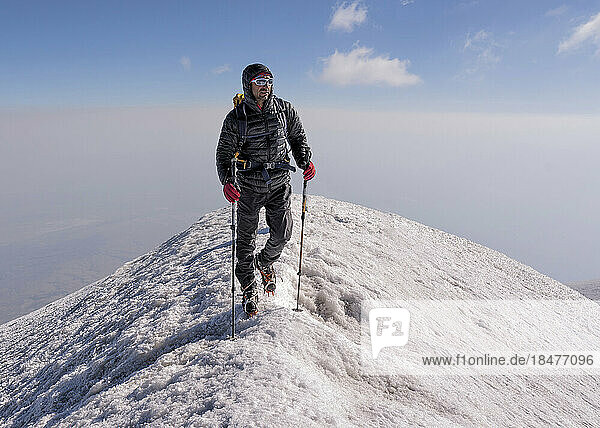 Man hiking on snow covered mountain at weekend