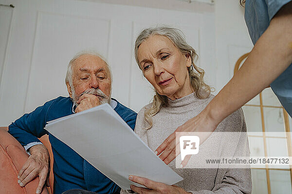 Ältere Frau liest medizinischen Bericht mit Mann zu Hause