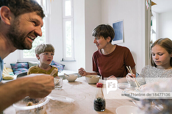 Parents eating food with children on dining table at home